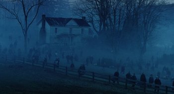 Movie still from “War of the Worlds” (2005), directed by Steven Spielberg – A group of people sitting on a bench in front of a house; Extreme Wide shot, High angle