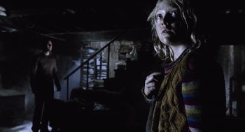 Movie still from “War of the Worlds” (2005), directed by Steven Spielberg – A woman standing in a dark room holding something; Medium shot, Low angle