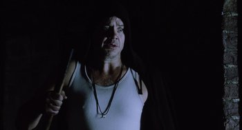 Movie still from “War of the Worlds” (2005), directed by Steven Spielberg – A man in a white tank top holding a knife in a dark room; Close Up shot, Low angle