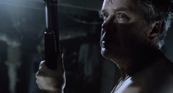 Movie still from “War of the Worlds” (2005), directed by Steven Spielberg – A person holding a gun in a dark room; Close Up shot, Low angle