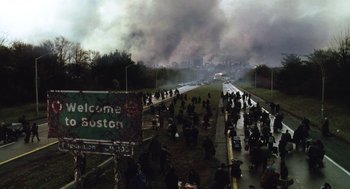 Movie still from “War of the Worlds” (2005), directed by Steven Spielberg – A large group of people on a road with smoke billowing in the background; Extreme Wide shot, High angle
