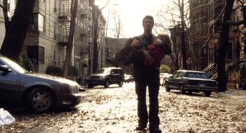 Movie still from “War of the Worlds” (2005), directed by Steven Spielberg – A man walking down the street with a baby in his arms; Wide shot, Low angle