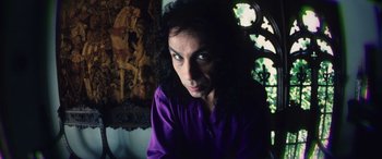 A woman in a purple shirt is looking at the camera