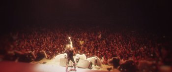A large crowd of people watching a band perform on a stage
