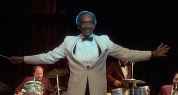 Movie still from “Dirty Dancing” (1987), directed by Emile Ardolino – An older man wearing a white suit and bow tie; Medium shot, Low angle