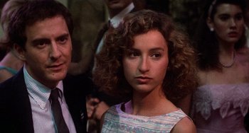 Movie still from “Dirty Dancing” (1987), directed by Emile Ardolino – A young woman with curly brown hair standing next to a man; Close Up shot, Over the shoulder angle