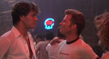 Movie still from “Dirty Dancing” (1987), directed by Emile Ardolino – A couple of men standing next to each other in a room; Close Up shot, Low angle