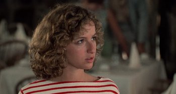 Movie still from “Dirty Dancing” (1987), directed by Emile Ardolino – A woman with curly brown hair wearing a red and white striped shirt; Close Up shot, Over the shoulder angle
