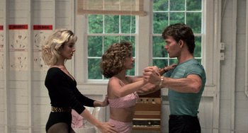 Movie still from “Dirty Dancing” (1987), directed by Emile Ardolino – Two women and a man dancing in front of a piano; Medium shot, Over the shoulder angle