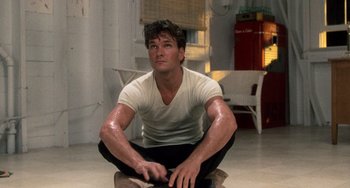 Movie still from “Dirty Dancing” (1987), directed by Emile Ardolino – A man sitting on the ground in a room; Medium shot, Low angle