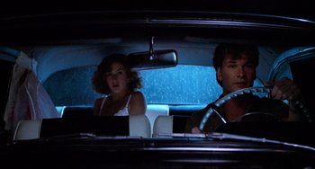 Movie still from “Dirty Dancing” (1987), directed by Emile Ardolino – A man and a woman in the back seat of a car; Medium shot, Over the shoulder angle