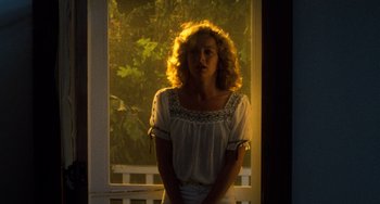Movie still from “Dirty Dancing” (1987), directed by Emile Ardolino – A woman standing in front of a window with sunlight coming through the window; Medium shot, Low angle