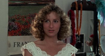 Movie still from “Dirty Dancing” (1987), directed by Emile Ardolino – A person with curly hair wearing a white dress; Close Up shot, Over the shoulder angle