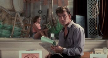 Movie still from “Dirty Dancing” (1987), directed by Emile Ardolino – A man sitting on the ground holding papers; Medium shot, Over the shoulder angle
