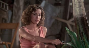 Movie still from “Dirty Dancing” (1987), directed by Emile Ardolino – A woman sitting on the ground with a plant in front of her; Close Up shot, Over the shoulder angle