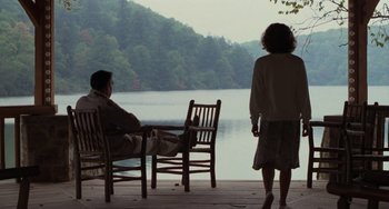 Movie still from “Dirty Dancing” (1987), directed by Emile Ardolino – A man and a woman sitting at a table near a body of water; Wide shot, High angle