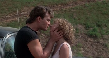 Movie still from “Dirty Dancing” (1987), directed by Emile Ardolino – A man and a woman kissing in front of a hill; Close Up shot, Low angle