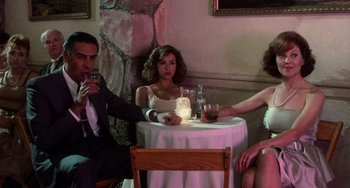 Movie still from “Dirty Dancing” (1987), directed by Emile Ardolino – A group of people sitting at a table with drinks; Wide shot, Low angle