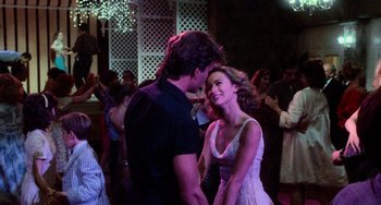 Movie still from “Dirty Dancing” (1987), directed by Emile Ardolino – A man and a woman are dancing together in front of a crowd of onlookers; Medium shot, Over the shoulder angle