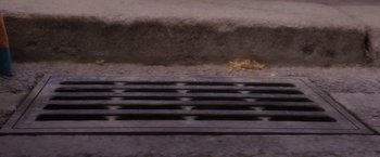 Movie still from “Disenchanted” (2022), directed by Adam Shankman – A grate on the side of the street; Extreme Close Up shot, Overhead angle