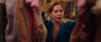 Movie still from “Disenchanted” (2022), directed by Adam Shankman – A red headed woman looking through a rack of clothes; Close Up shot, Over the shoulder angle