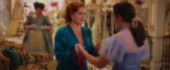 Movie still from “Disenchanted” (2022), directed by Adam Shankman – A woman in a blue dress is holding her hands with another woman in a blue dress; Medium shot, Over the shoulder angle