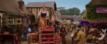 Movie still from “Disenchanted” (2022), directed by Adam Shankman – A woman standing on top of a crate of apples; Wide shot, Low angle