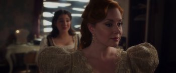 Movie still from “Disenchanted” (2022), directed by Adam Shankman – A woman with red curly hair and wearing a gold dress; Close Up shot, Over the shoulder angle
