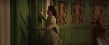 Movie still from “Disenchanted” (2022), directed by Adam Shankman – A woman dressed in a long dress is opening a door; Medium shot, Over the shoulder angle