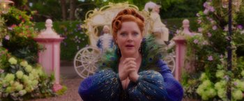 Movie still from “Disenchanted” (2022), directed by Adam Shankman – A woman in a peacock costume with her hands folded in front of her face; Medium shot, Over the shoulder angle