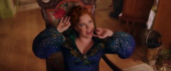 Movie still from “Disenchanted” (2022), directed by Adam Shankman – A woman in a peacock inspired dress is making a funny face; Medium shot, Low angle