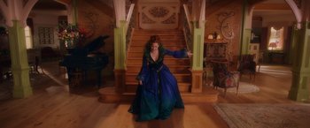 Movie still from “Disenchanted” (2022), directed by Adam Shankman – A woman in a blue dress standing in front of a staircase; Wide shot, High angle