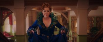 Movie still from “Disenchanted” (2022), directed by Adam Shankman – A woman in a peacock costume sitting in a chair; Medium shot, Over the shoulder angle