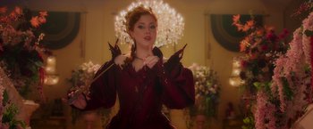 Movie still from “Disenchanted” (2022), directed by Adam Shankman – A woman in a red dress holding her hands up; Medium shot, Over the shoulder angle
