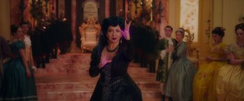 Movie still from “Disenchanted” (2022), directed by Adam Shankman – A woman in a black dress and a purple wig; Medium shot, Over the shoulder angle
