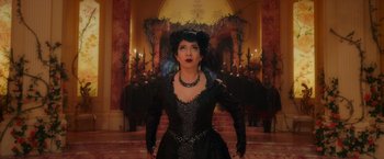 Movie still from “Disenchanted” (2022), directed by Adam Shankman – A woman in a black dress standing in front of a fireplace; Medium shot, Low angle