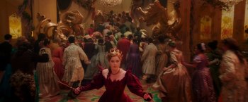 Movie still from “Disenchanted” (2022), directed by Adam Shankman – A woman in a red dress and a crown in front of a crowd of people; Wide shot, High angle