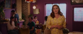 Movie still from “Disenchanted” (2022), directed by Adam Shankman – A woman in a yellow dress standing in front of a table; Medium shot, Over the shoulder angle