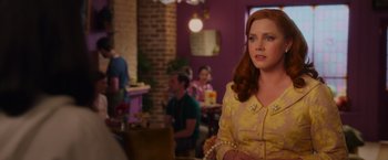 Movie still from “Disenchanted” (2022), directed by Adam Shankman – A woman in a yellow dress in front of a brick wall; Medium shot, Over the shoulder angle