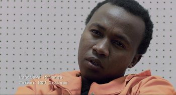 Movie still from “District 9” (2009), directed by Neill Blomkamp – A person wearing an orange jacket; Close Up shot, Over the shoulder angle