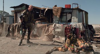 Movie still from “District 9” (2009), directed by Neill Blomkamp – A man standing next to another man in a field; Wide shot, Over the shoulder angle