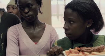Movie still from “District 9” (2009), directed by Neill Blomkamp – Two people sitting at a table with a plate of food in front of them; Close Up shot, Over the shoulder angle