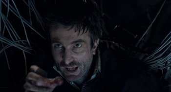 Movie still from “District 9” (2009), directed by Neill Blomkamp – A person in a dark room; Close Up shot, Overhead angle