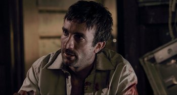Movie still from “District 9” (2009), directed by Neill Blomkamp – A person wearing a shirt with blood all over it; Close Up shot, Over the shoulder angle