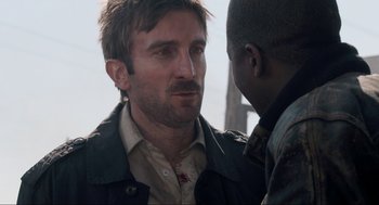 Movie still from “District 9” (2009), directed by Neill Blomkamp – A man with a beard talking to another man; Close Up shot, Over the shoulder angle