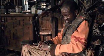 Movie still from “District 9” (2009), directed by Neill Blomkamp – A man sitting in front of a bar using a cell phone; Medium shot, High angle