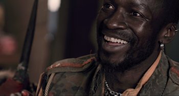 Movie still from “District 9” (2009), directed by Neill Blomkamp – A person with a beard smiling; Close Up shot, Over the shoulder angle