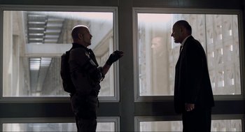 Movie still from “District 9” (2009), directed by Neill Blomkamp – Two men are talking in front of a window; Medium shot, Over the shoulder angle