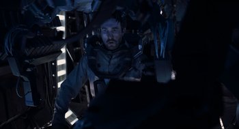 Movie still from “District 9” (2009), directed by Neill Blomkamp – A man sitting inside of a vehicle in the dark; Medium shot, Over the shoulder angle