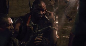 Movie still from “District 9” (2009), directed by Neill Blomkamp – A man holding a gun while talking on a phone; Close Up shot, Over the shoulder angle